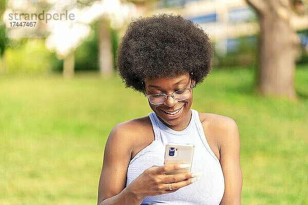 Frau mit Afro-Haaren  die ihr Smartphone benutzt