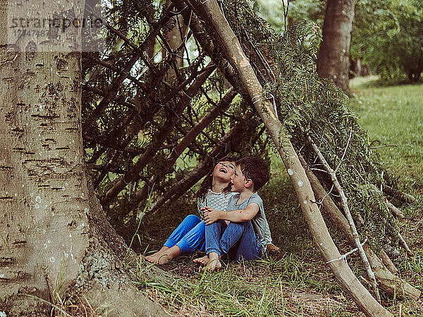 Kaukasisches Kind in einer Hütte aus Zweigen und Blättern