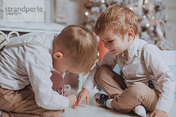 Fröhliche süße Kinderjungen  die Geschenke unter dem Weihnachtsbaum öffnen.