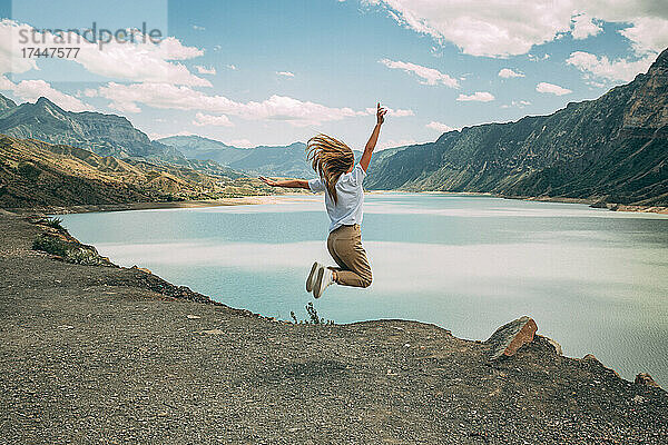 Das Mädchen springt voller Freude vor dem Hintergrund der Berge