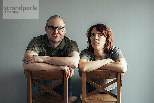 Porträt eines Mannes und einer Frau  die auf Stühlen sitzen und in die Kamera schauen.
