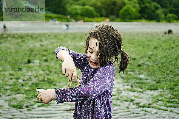 Ausgeschnittenes Porträt eines jungen Mädchens  das lacht  während es eine Krabbe hält