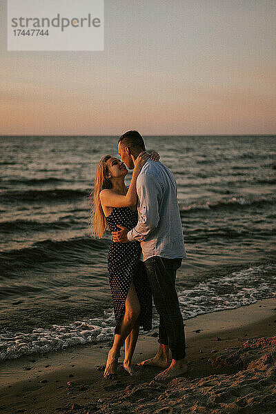 Ein verliebtes Paar steht umarmt am Meer.