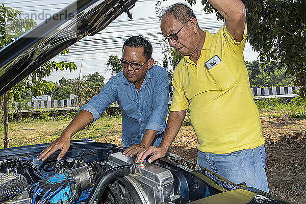 Zwei Männer schauen in Thailand unter die Motorhaube eines amerikanischen Muscle-Cars