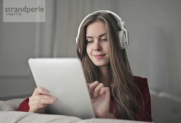Junge Frau benutzt ein Tablet und hört Musik
