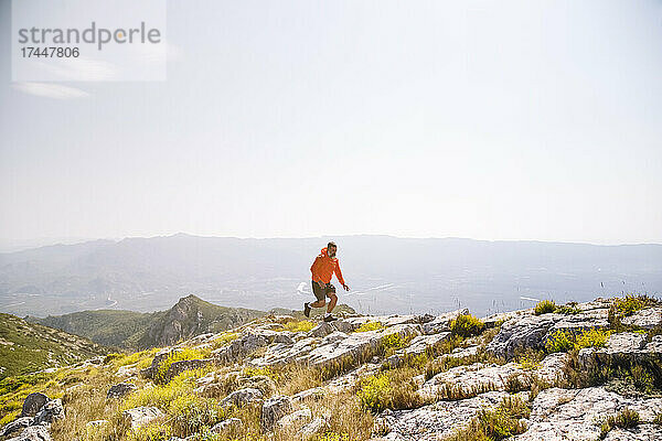 Männlicher Wanderer läuft auf Felsen im Berg
