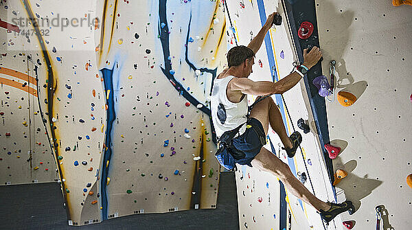 Mann klettert an der Indoor-Kletterwand in London