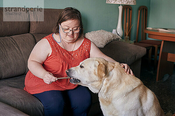 Erwachsene Frau mit Down-Syndrom hat Spaß mit ihrem Hund zu Hause