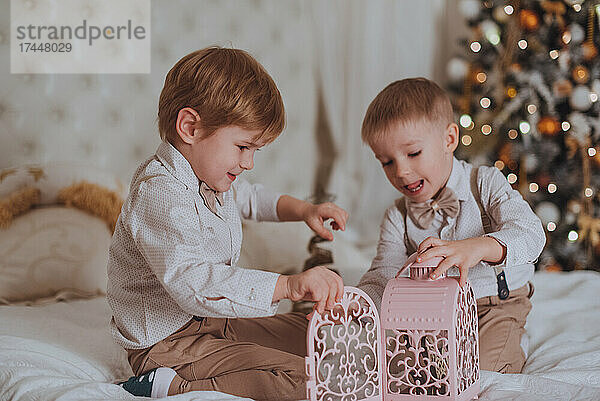 Fröhliche süße Kinderjungen  die Geschenke unter dem Weihnachtsbaum öffnen.