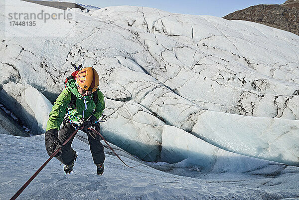 Frau steigt in Gletscherspalte am Svinafellsjökull-Gletscher / Island auf