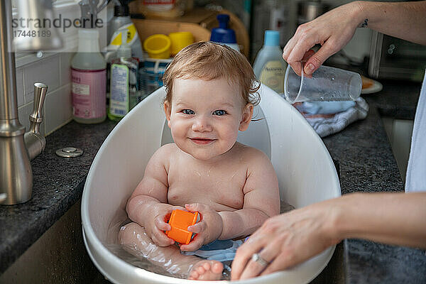 Glücklicher kleiner Junge  der im Waschbecken badet.