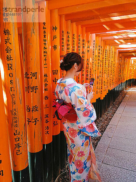 Mädchen im Kimono blickt auf ein japanisches Handy