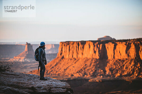 Eine Wanderin blickt bei Sonnenuntergang auf den Canyonlands-Nationalpark in Utah