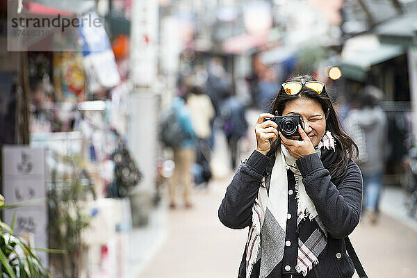 Frau  die in Tokio ein Foto mit einer digitalen spiegellosen Kamera macht