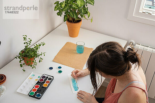 Frau malt mit Wasserfarben in ihrem Atelier zu Hause