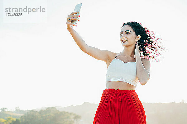 Porträt einer jungen Frau  die ein Selfie mit dem Mobiltelefon macht