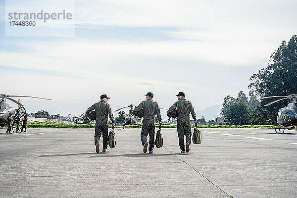 Drei Militärangehörige laufen auf einer Landebahn auf die Hubschrauber zu