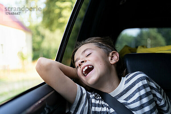Ein kleiner Junge genießt den warmen Wind aus dem offenen Autofenster