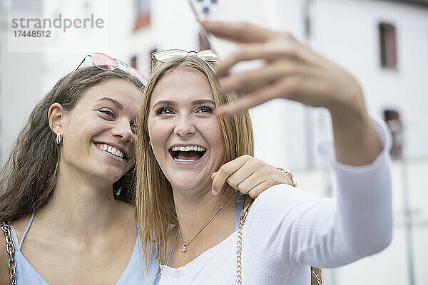 Zwei junge Frauen machen Selfies mit Mobiltelefonen in der Umgebung