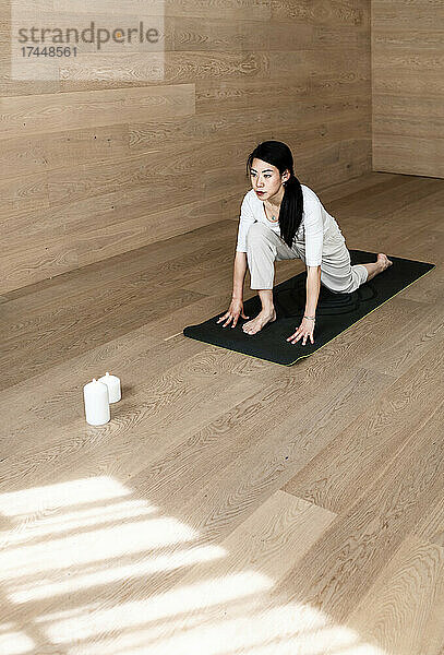 Junge konzentrierte Frau macht Yoga-Übungen  während sie auf dem Boden sitzt