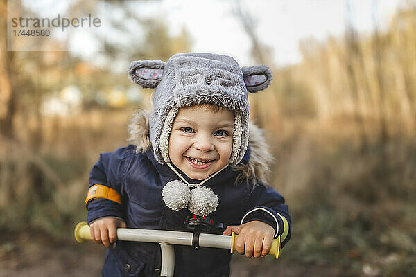Kleiner Junge draußen im Wald auf dem Fahrrad lächelnd