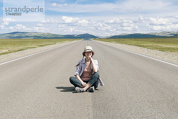 Reisende Frau sitzt auf der Bergstraße. Republik Altai.