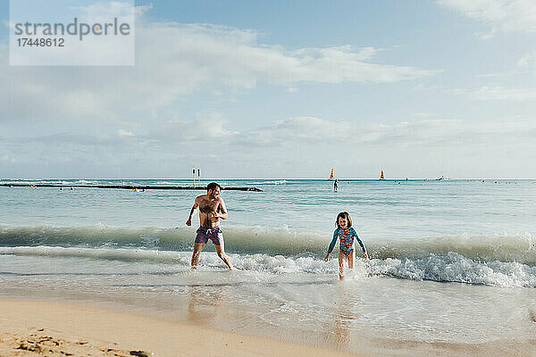 Vater und Tochter spielen im Meer am Strand von Waikiki