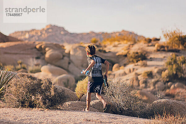 Junge läuft mit Pfeil und Bogen durch die Wüste.