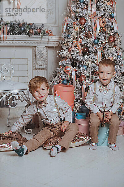 Fröhliche süße Kinderjungen  die Geschenke unter dem Weihnachtsbaum öffnen.