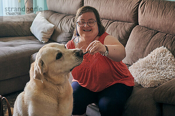 Erwachsene Frau mit Down-Syndrom hat Spaß mit ihrem Hund zu Hause