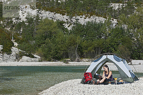 Frau liest zu zehnt auf einem abgelegenen Campingplatz im Verdon Canyon