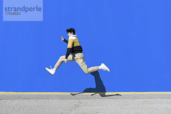 Junger Mann springt auf den Stadtmauerhintergrund