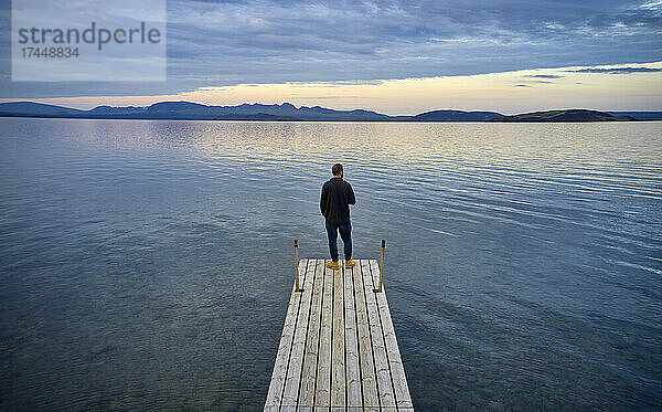 Mann steht auf Pier in der Nähe des Sees