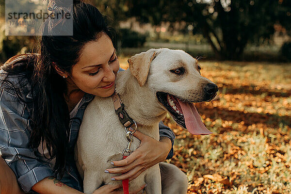 Glückliche Frau umarmt ihren Labrador-Welpen im Freien
