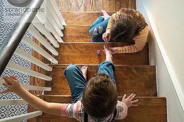 Ruhiger Moment  in dem die Schwester ihrem Bruder auf der Treppe eine Pediküre gibt