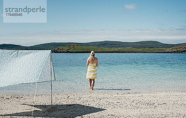 Eine Frau stand an einem schönen Tag am Strand und blickte auf das Wasser