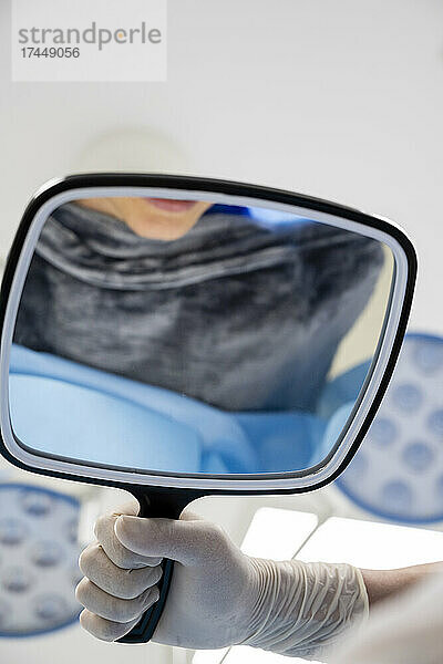 Auf der Trage liegend blickt eine Patientin in den Spiegel