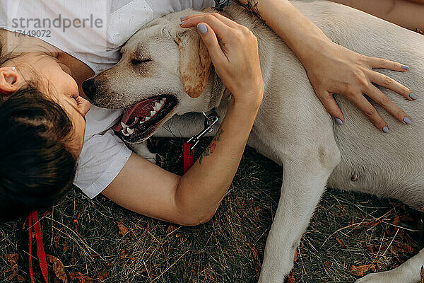 Frau umarmt ihren Labrador im Freien. Lebensstile und Haustierpflegekonzept.