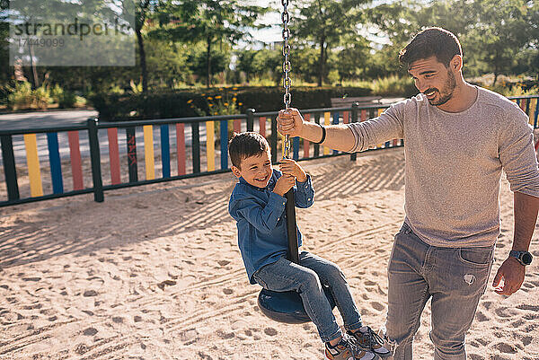 Vater und Sohn spielen mit einer Seilrutsche in einem Park