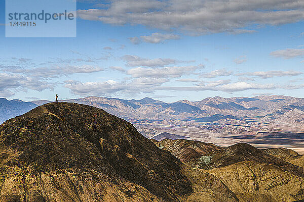 Eine kleine  winzige  einsame Person steht auf dem Gipfel in der Weite des Death Valley.