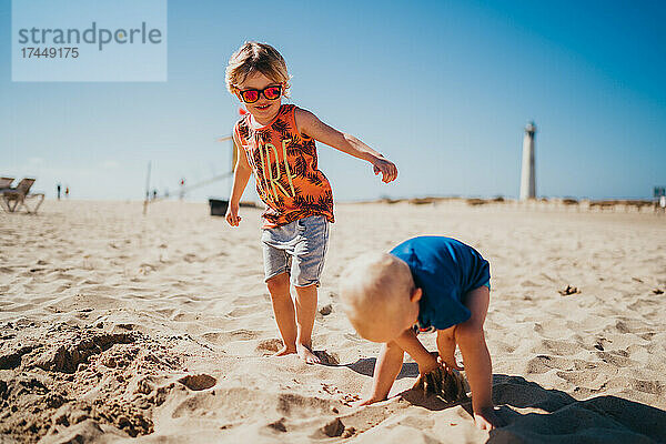 Kleine Kinder spielen an einem sonnigen Tag mit Sand am Leuchtturmstrand