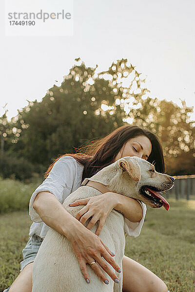 Glückliche Frau umarmt ihren Labrador-Welpen im Freien