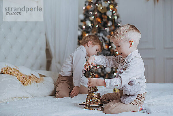 Fröhliche süße Kinderjungen  die Geschenke unter dem Weihnachtsbaum öffnen.