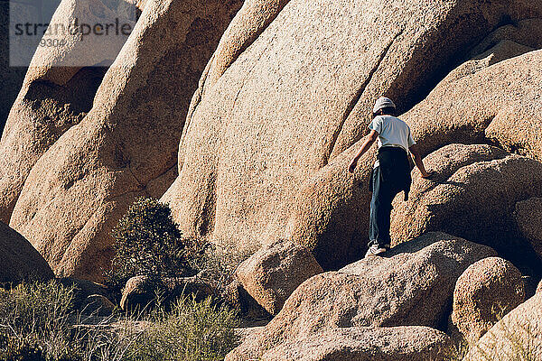 Älterer Junge geht zwischen großen Felsen in der Wüste spazieren.