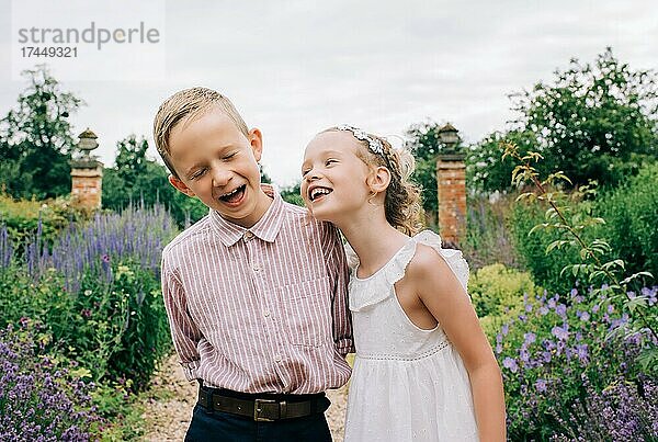 Junge und Mädchen lachen glücklich in einem wunderschönen Blumenfeld