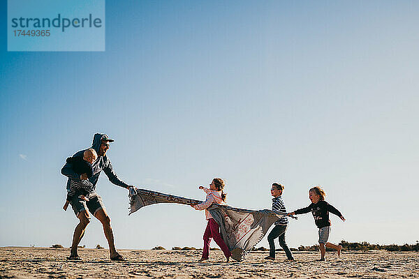 Vater und Kinder spielen am Strand und haben Spaß auf Fuerteventura