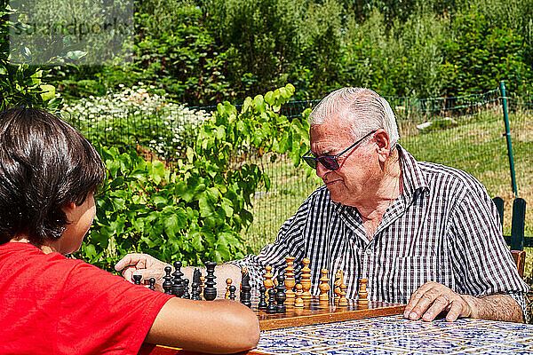 Großvater und Enkel spielen Schach im Garten