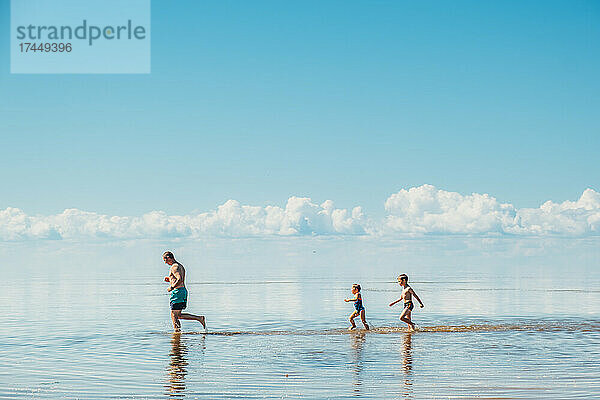 Vater und Kinder laufen und spielen tagsüber auf dem See.
