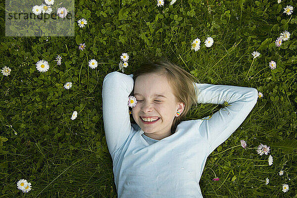 Porträt eines fröhlichen Mädchens  das im Gras liegt.