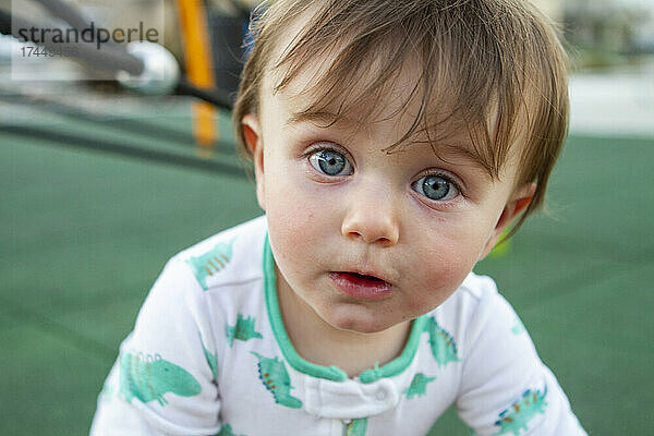 Baby boy playing on the playground looking at the camera